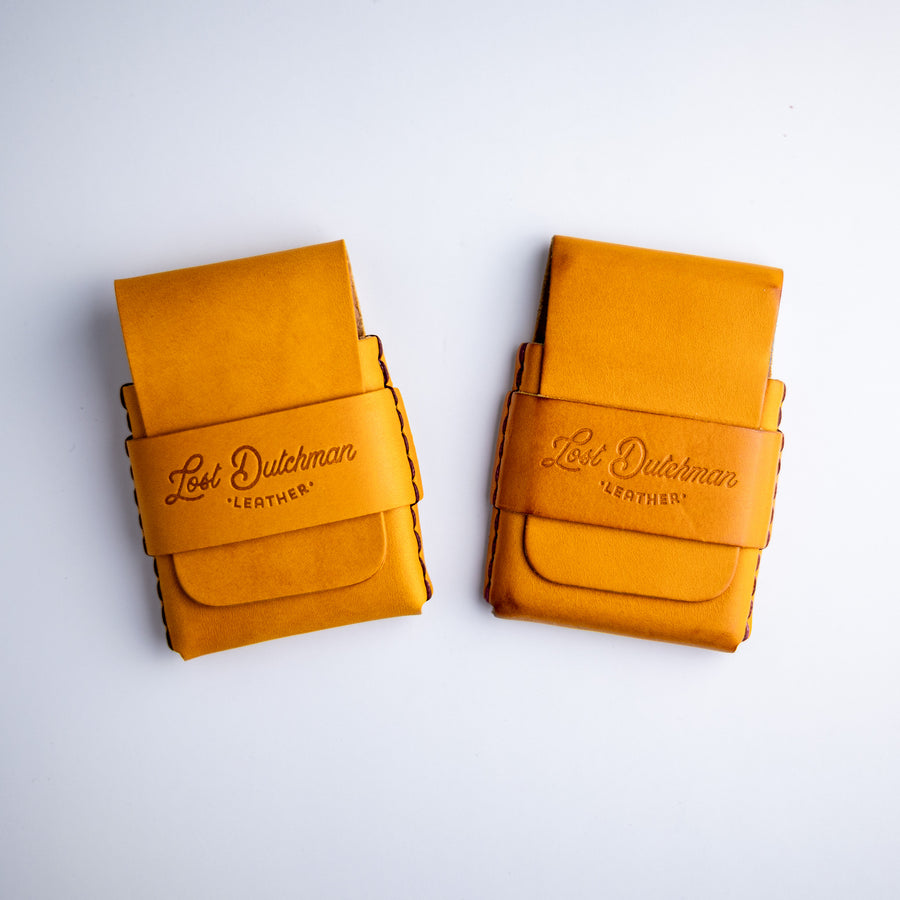 Two mustard-yellow leather wallets on a pale background