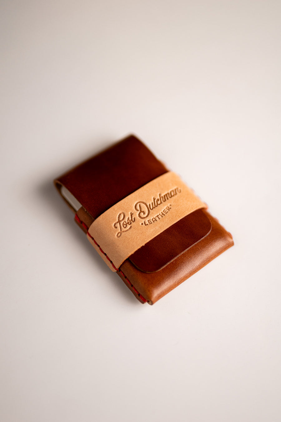 Brown leather wallet with a tan wrap band