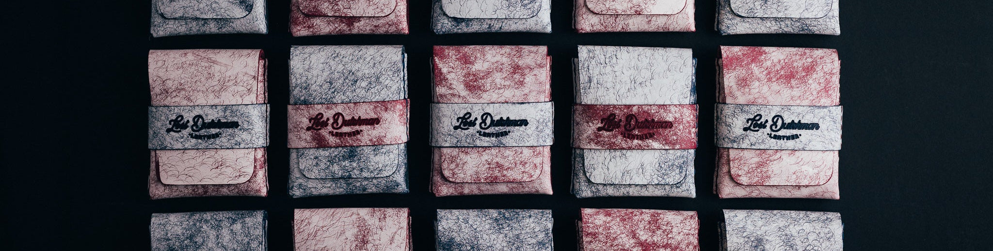 Rows of pale patterned leather wallets with dark bands