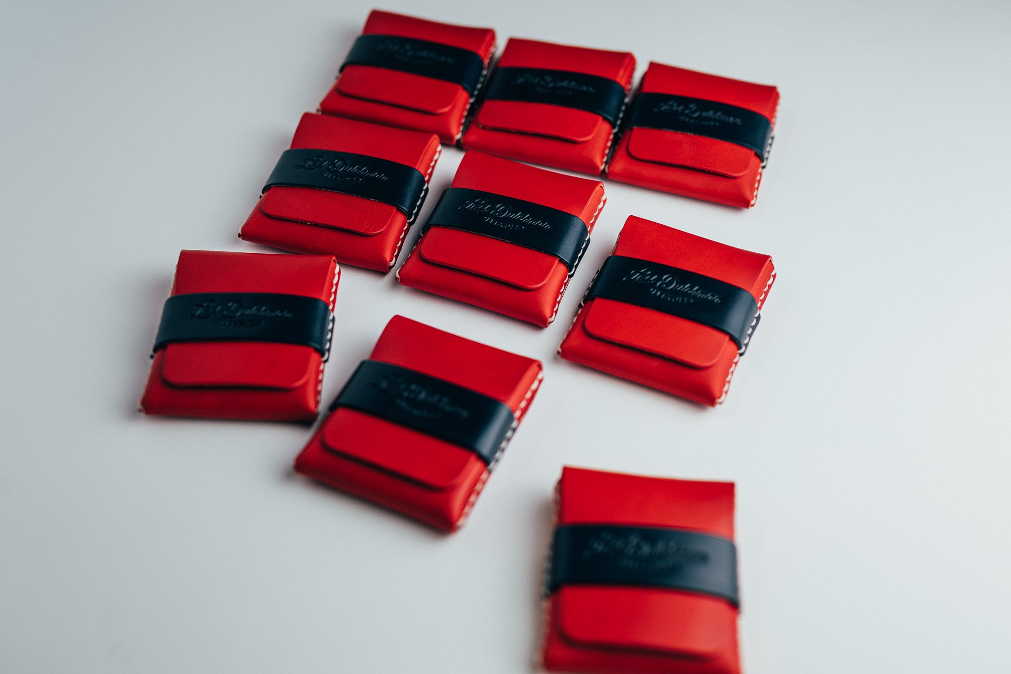 Assorted red leather wallets arranged on a white surface