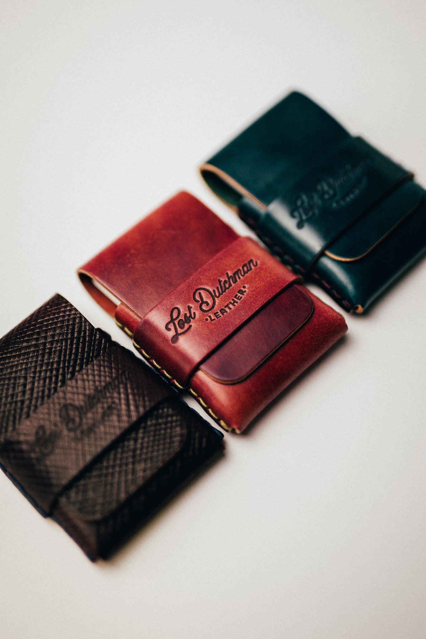 Three folded leather wallets on a white surface