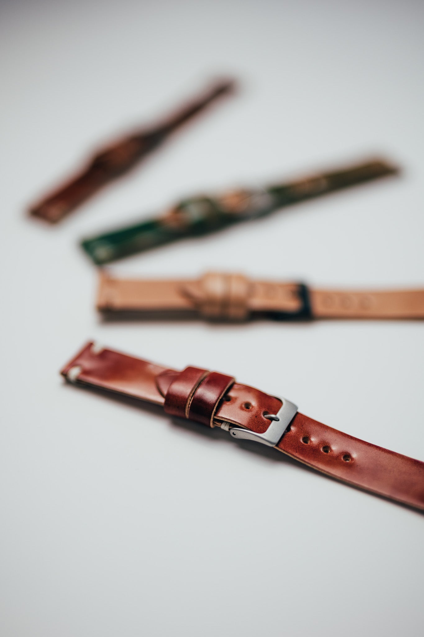 Two leather watch straps on a white surface
