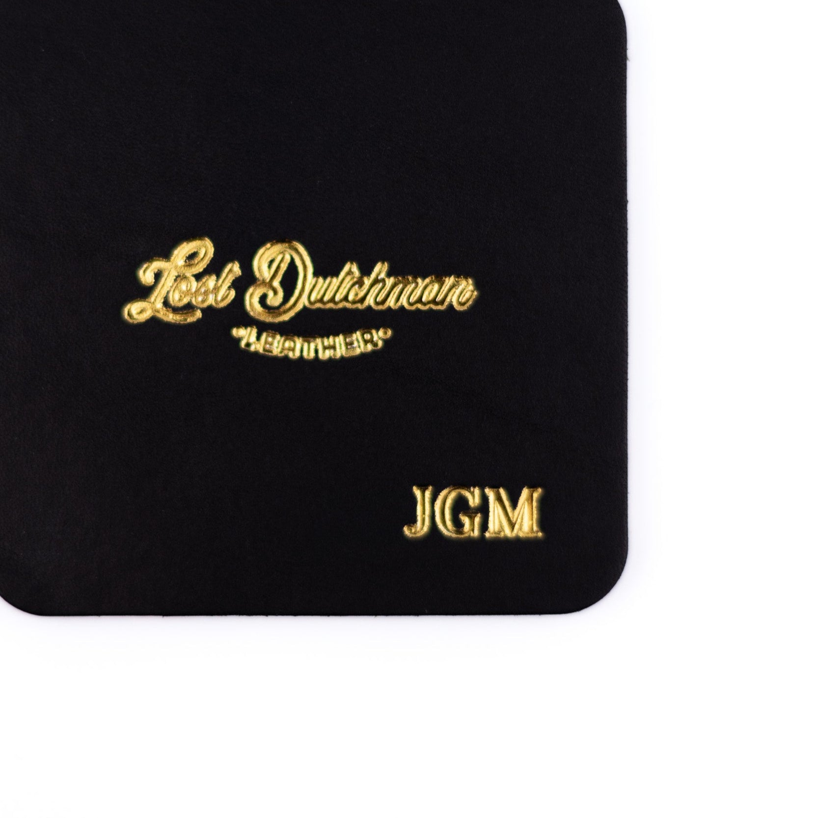 Black coaster with gold text on a white background