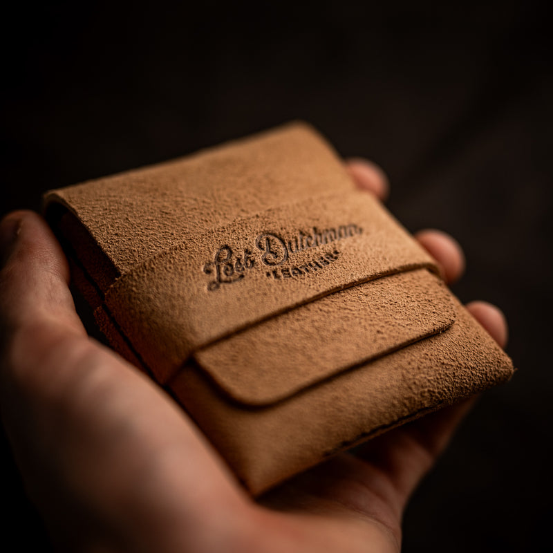 Hands holding a tan leather card holder with an embossed logo