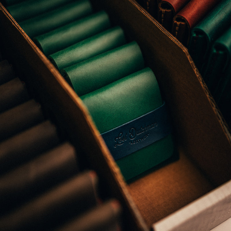 Green and brown leather card holders arranged in a display tray