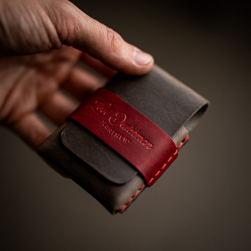 Hand holding grey and red leather card holders