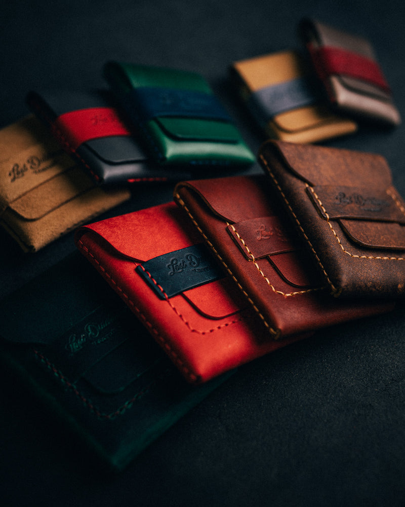 Assorted colourful leather card holders arranged on a dark surface