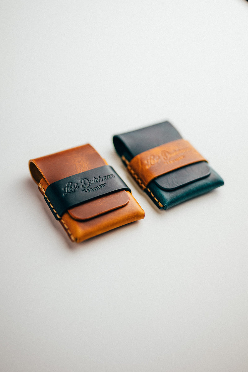 Two compact leather card holders on a white surface, one dark teal and one brown