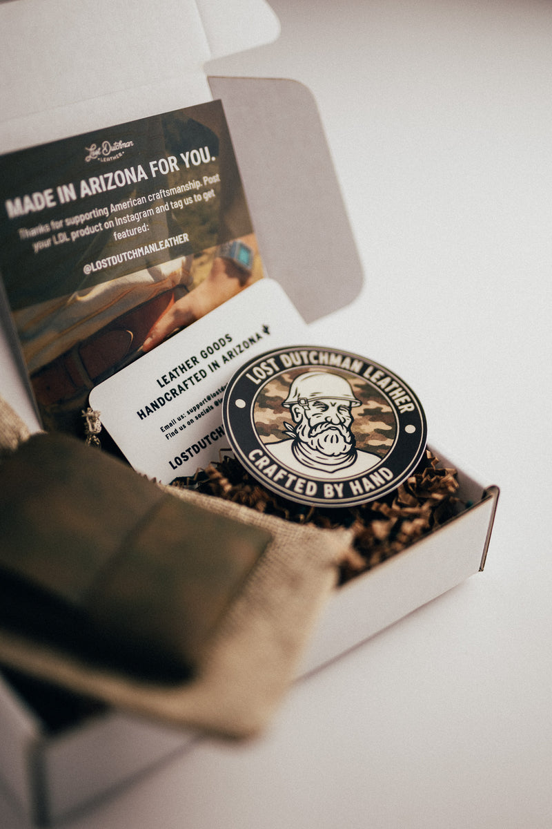 Open gift box containing Lost Dutchman Leather cards and a round “Crafted by Hand” sticker