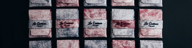 Rows of pale patterned leather wallets with dark bands