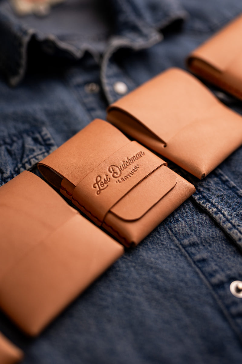 Tan leather wallet tucked into a denim shirt pocket