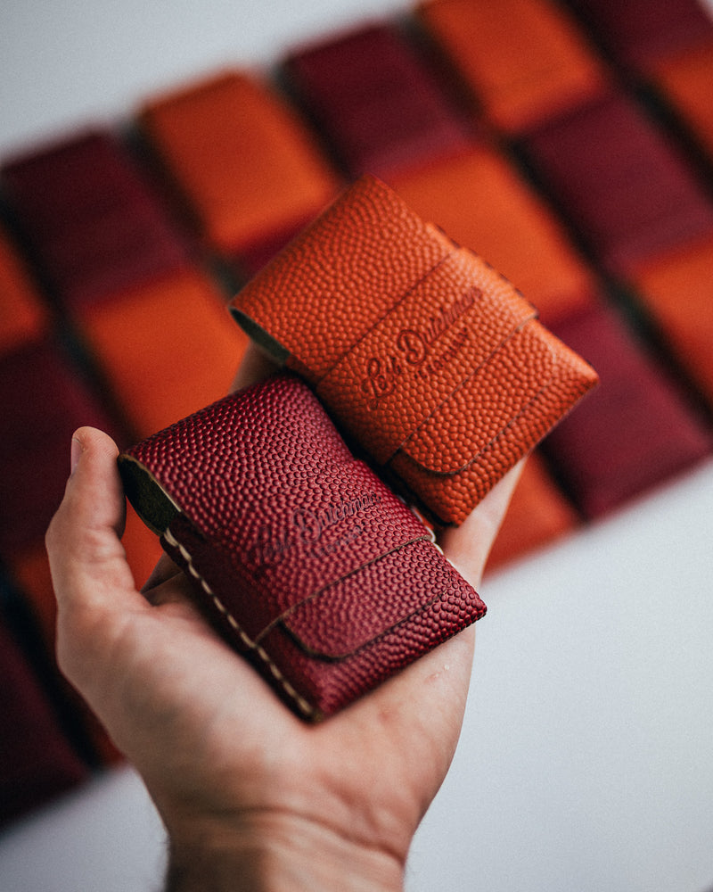 Hand holding two folded leather wallets