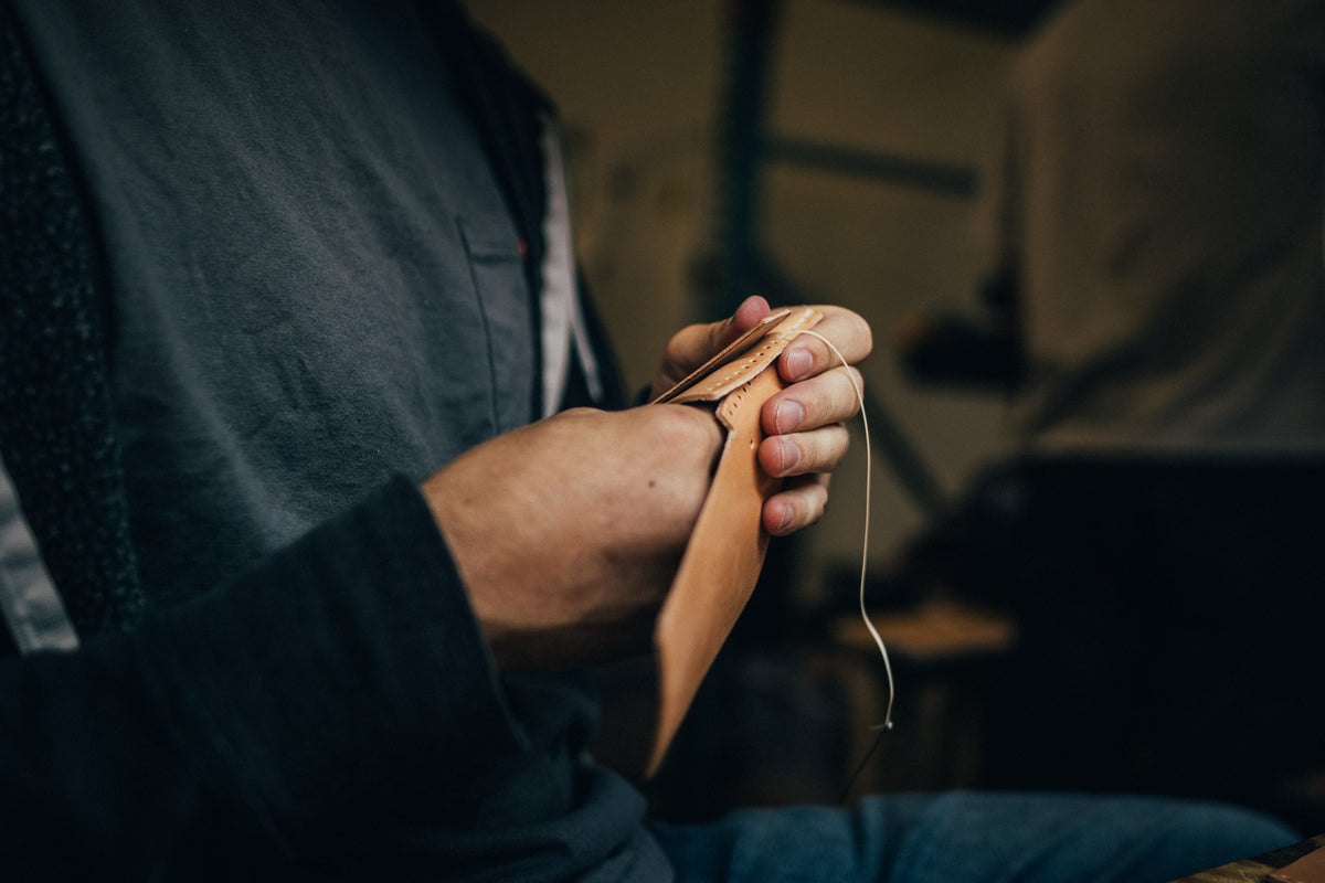 Craftsperson stitching leather by hand