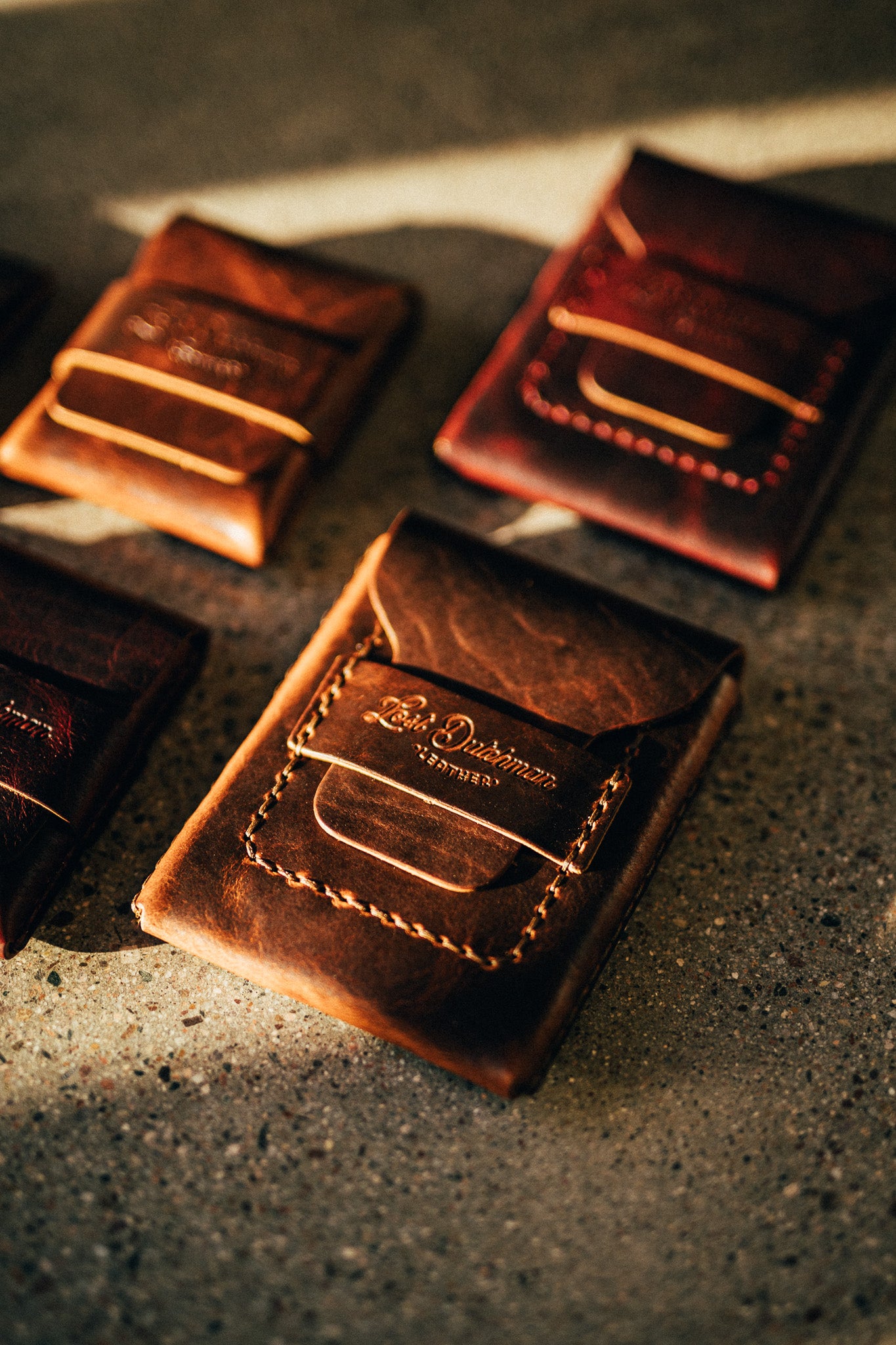 Four dark leather wallets with tan stitching