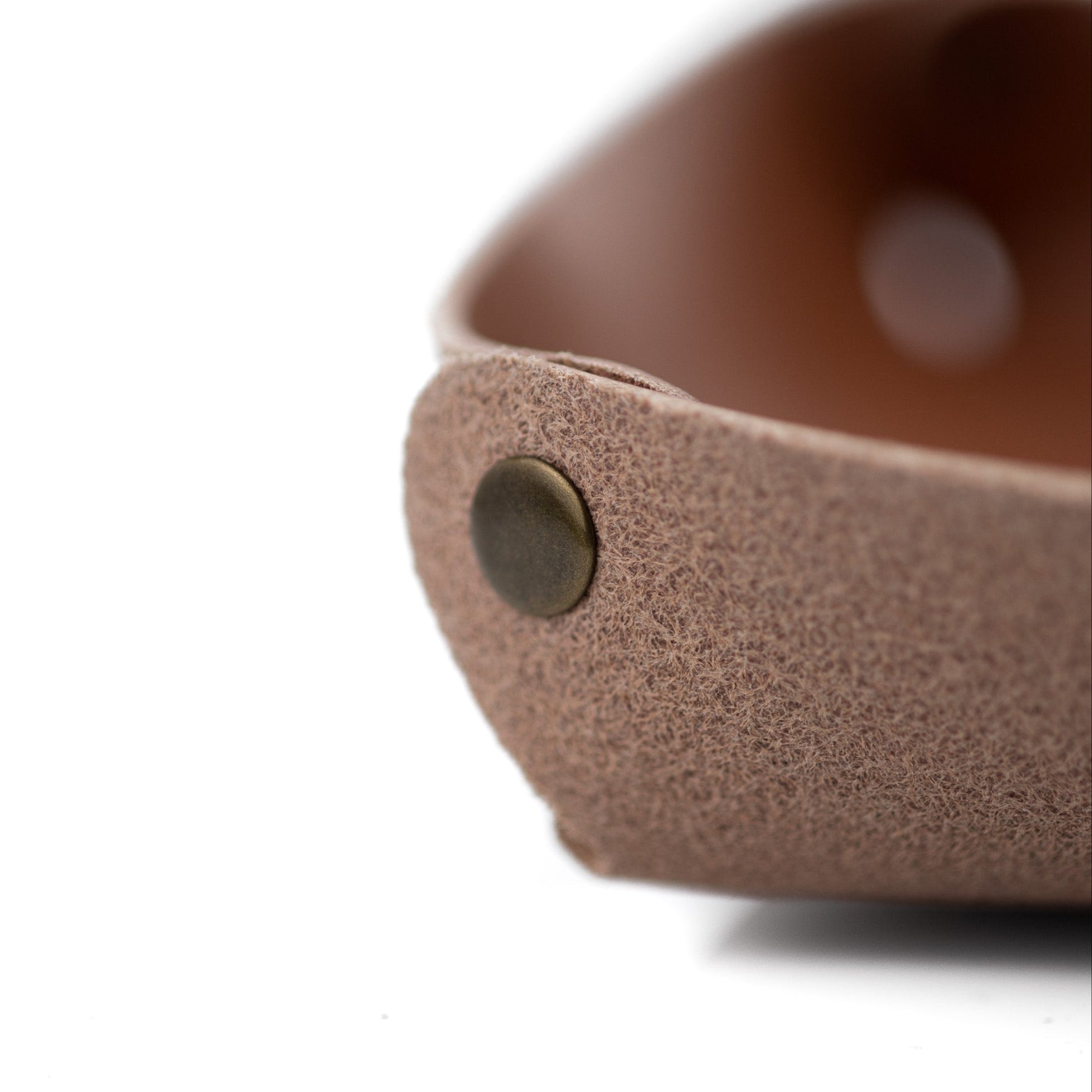 Close-up of a brown leather valet tray with a brass snap on a white background