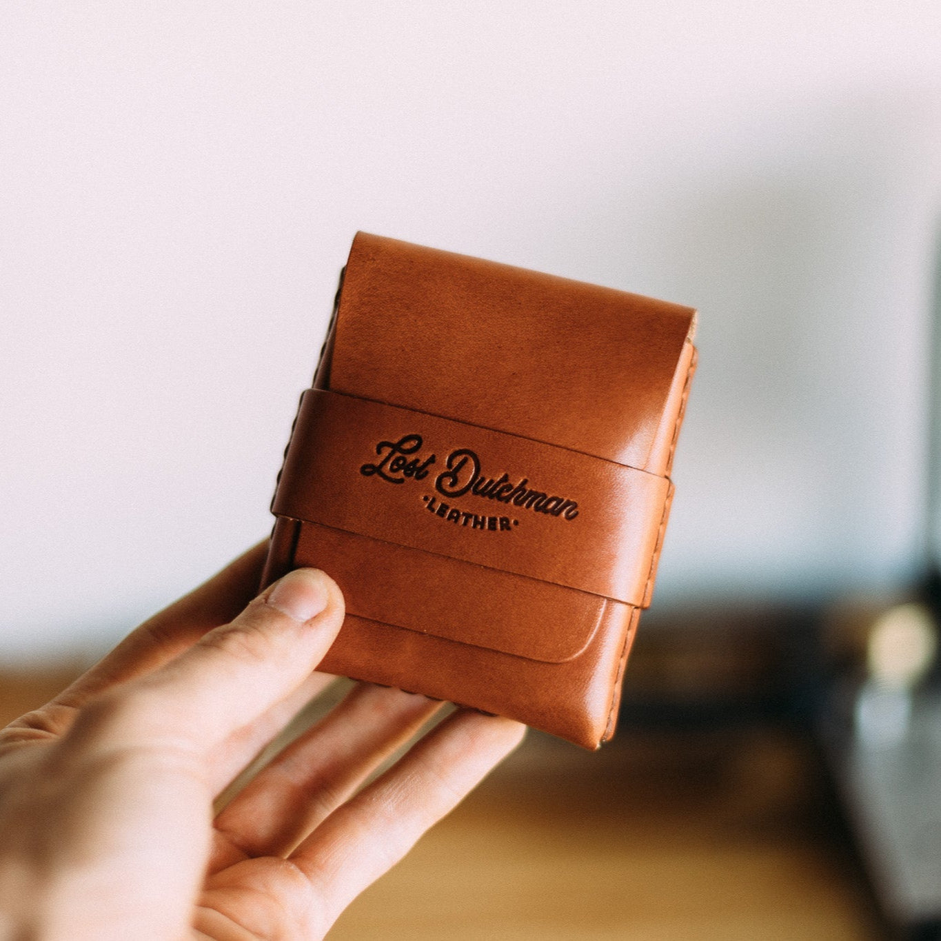 Hand holding a "Lost Dutchman Leather" brown leather wallet.
